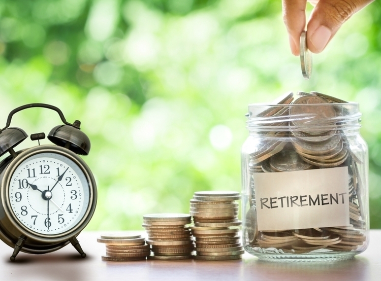 Hand putting money in a jar labeled "retirement" with a clock next to it.